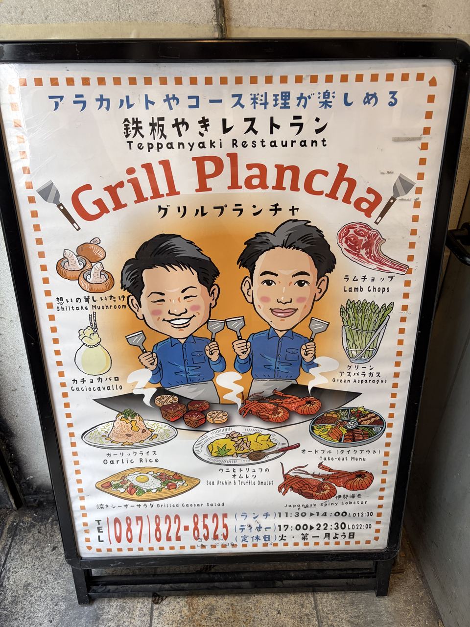 グリルプランチャの店頭に立つ手描きの看板メニュー