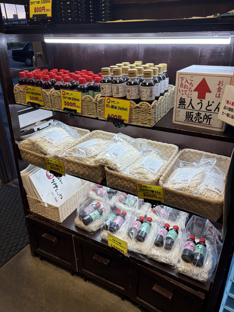店先の無人うどん販売所に並ぶ持ち帰り用のうどんとだし醤油
